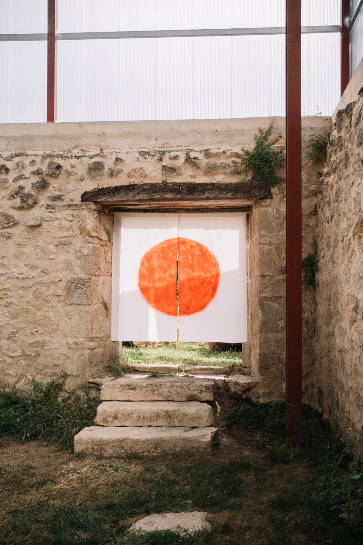 Sol naranja pintado sobre tela en muro de piedra